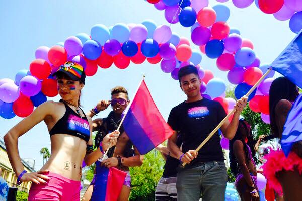 Photo of Damian at LA Pride holding a bi flag.
