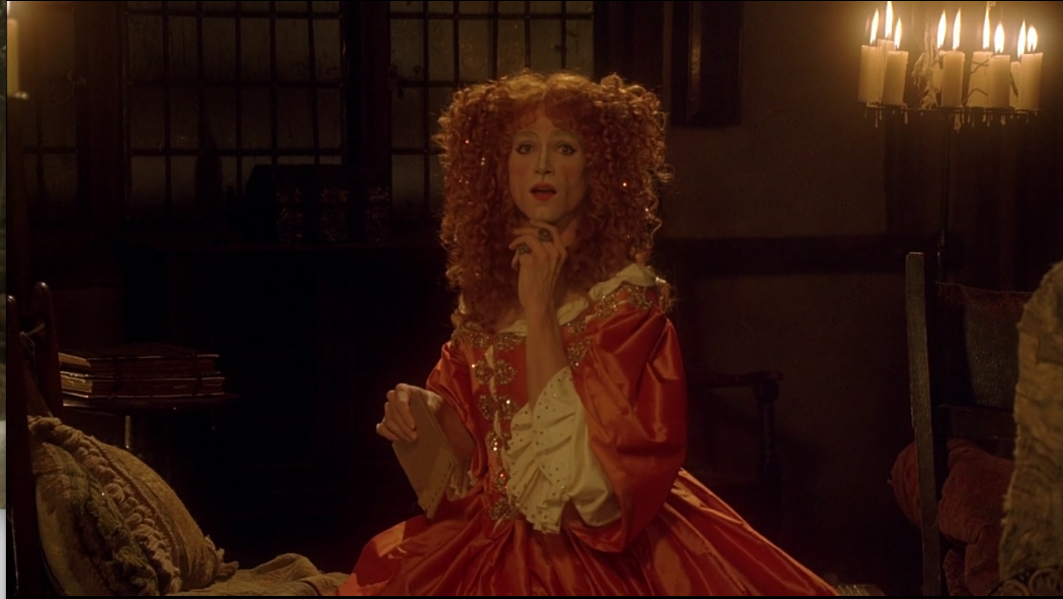 Ned se visti&oacute; de mujer, con peluca maquillada y vestido. Tiene una expresi&oacute;n de asombro con una mano en la cara.