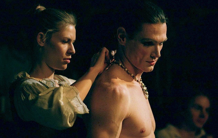 Mar&iacute;a ayuda a un Ned sin camisa a quitarse parte de un collar y un disfraz de detr&aacute;s de &eacute;l.