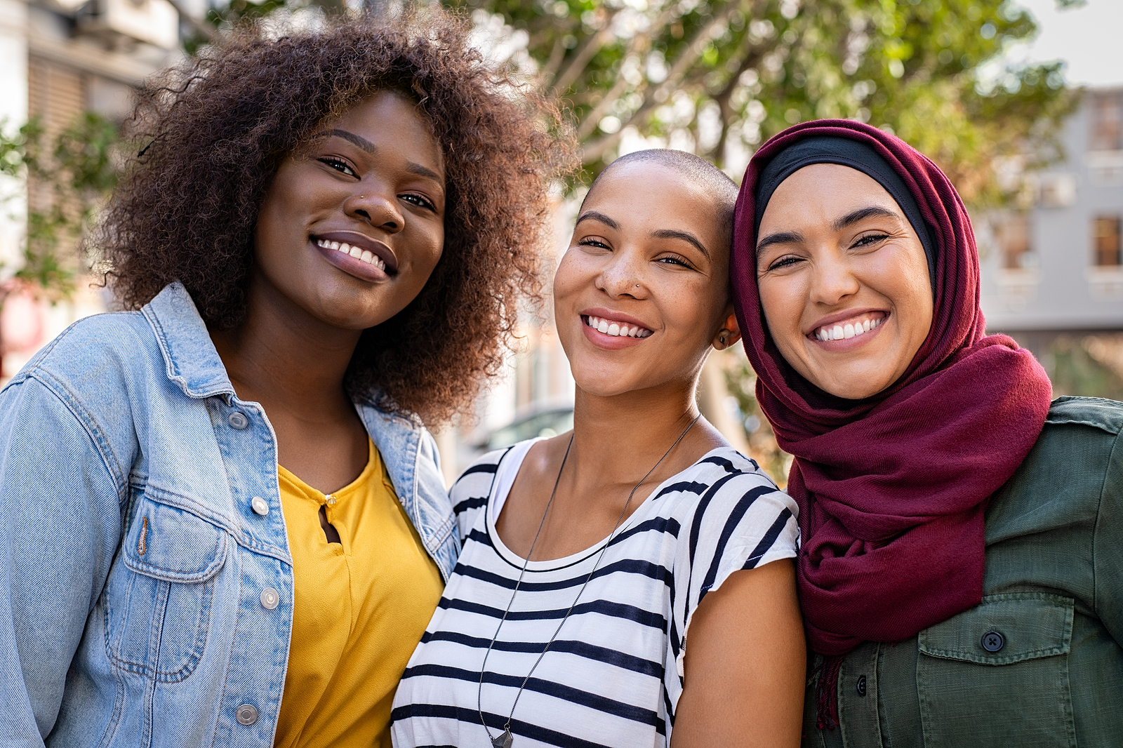 Tres mujeres vestidas con colores alegres, sonriendo hac&iacute;a la c&aacute;mara.