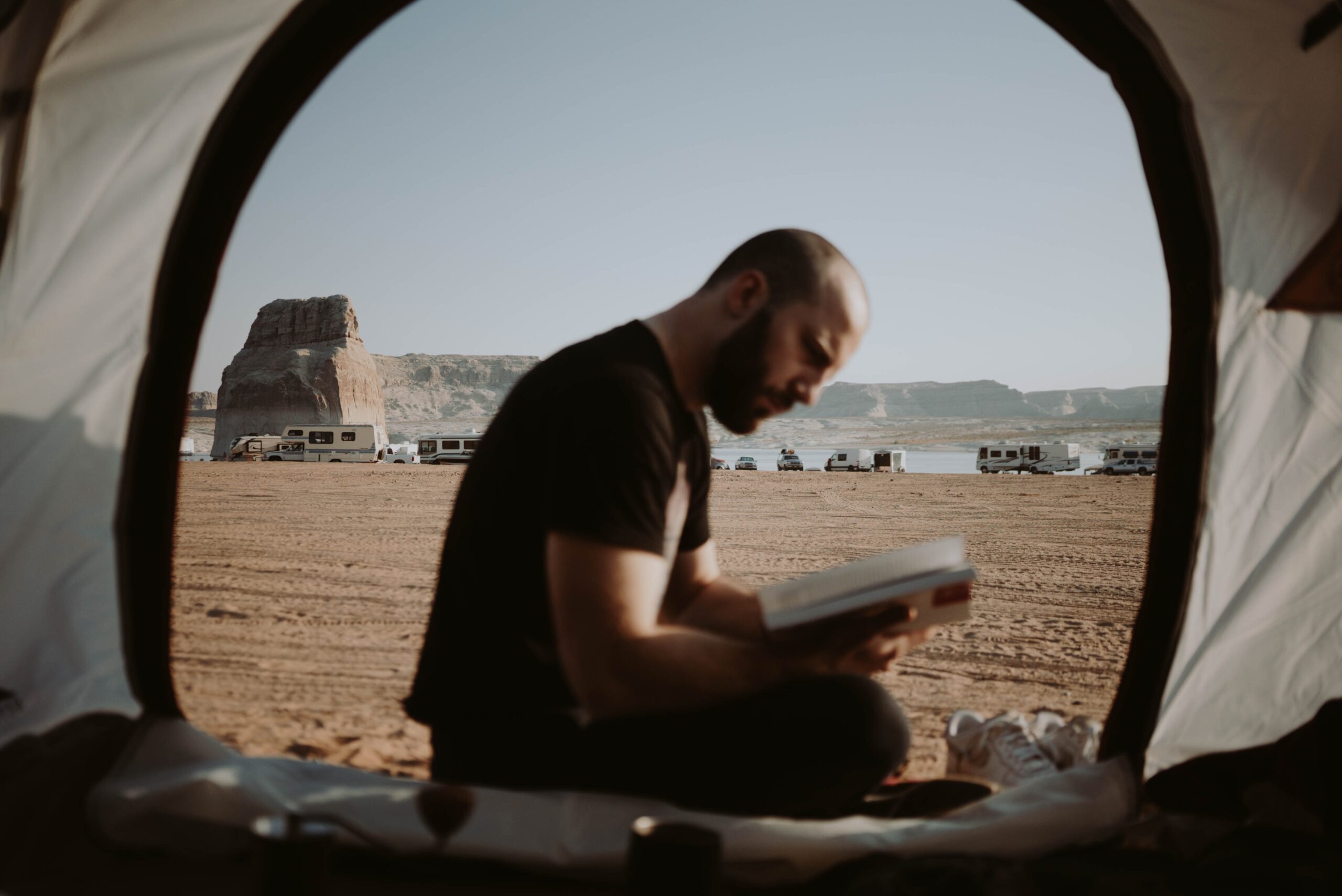 Un hombre vestido de negro, sentado leyendo un libro.