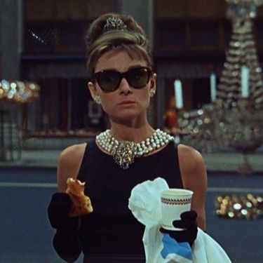 Aubrey as Holly, in her iconic black outfit, sunglasses, pearl necklaces and black gloves.