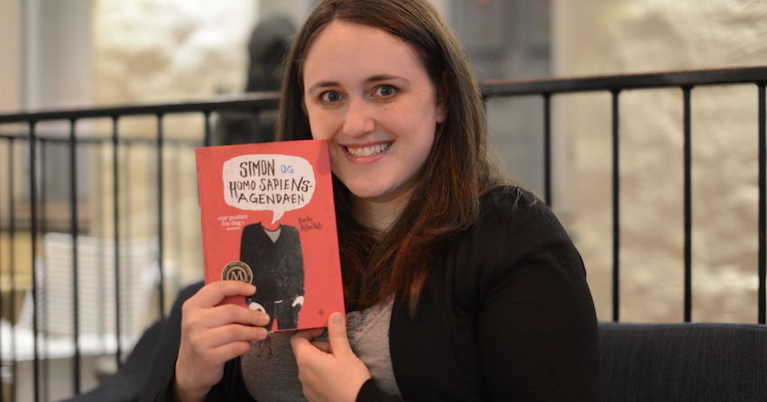Becky Albertalli mostrando su libro de Simon a la c&aacute;mara y sonriendo