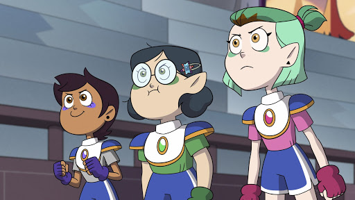 Luz junto a dos amigas de pie confiadamente con una armadura de pecho.