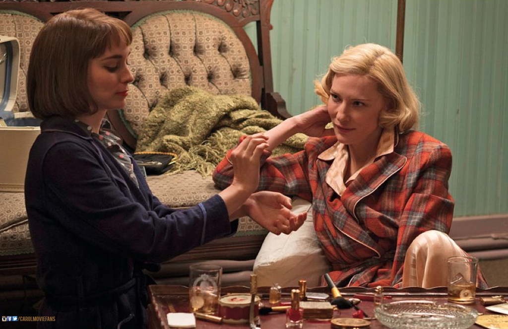 Carol looking lovingly at Th&eacute;rese while she tries on perfume on her wrists.