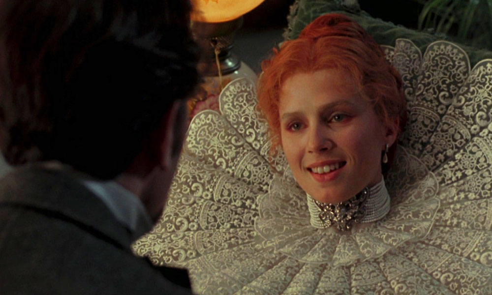 Lucy con un gran vestido victoriano sonríe a alguien fuera de cámara.