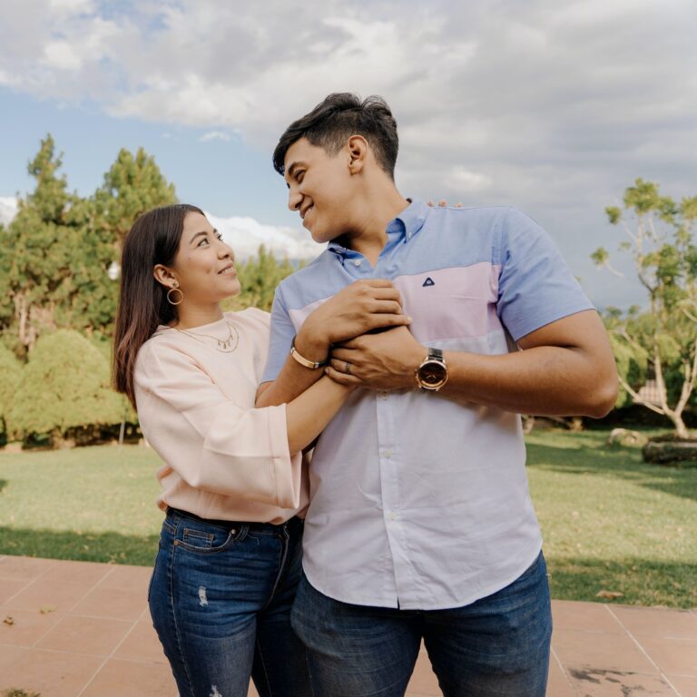 A young latin couple has an intimate moment holding onto eachother in the outdoors.