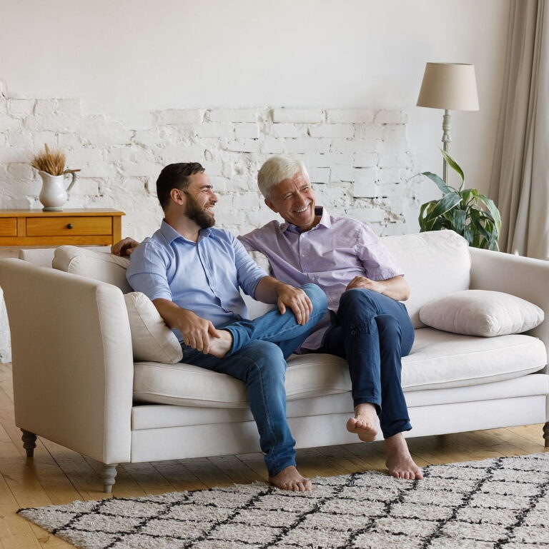 Cheerful man his senior father talking sit on sofa.