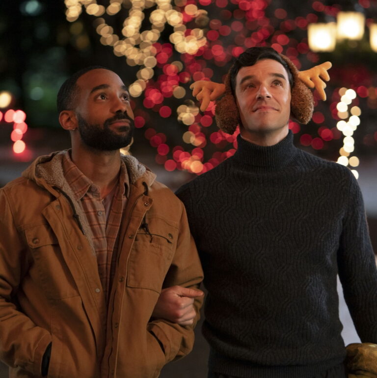 Tim and Peter walking together while holding onto eachothers arms, looking at the christmas decorations.