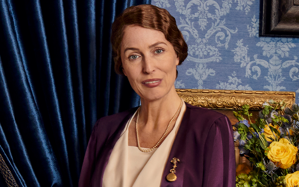 Eleanor from the series sitting in posing on a chair smiling.