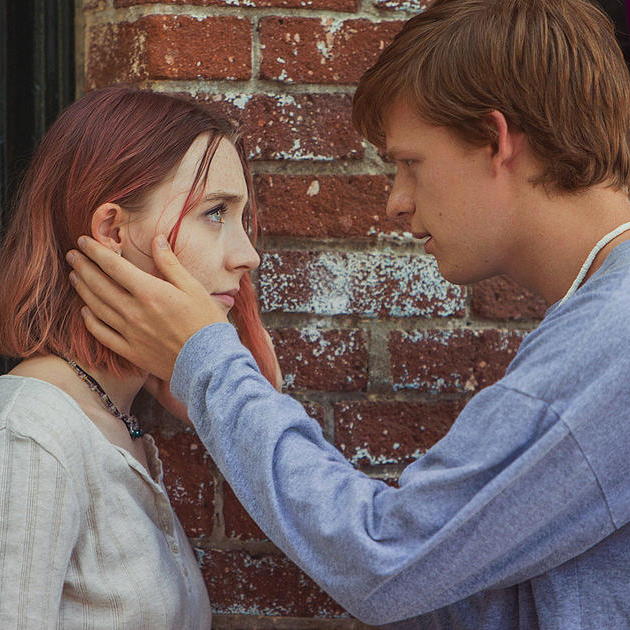 Danny facing Lady Bird with both hands on her face both looking into their eyes.