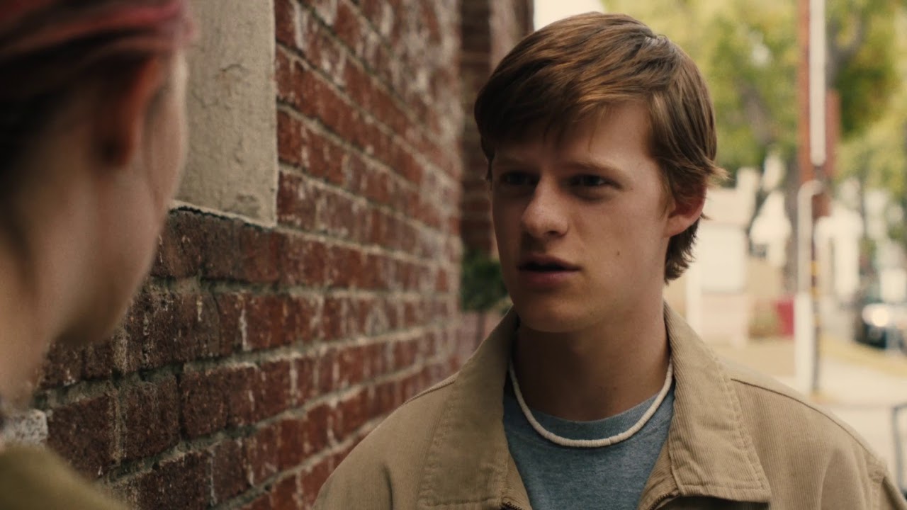 Danny talking to Lady bird next to a brick wall with a concerned expression.