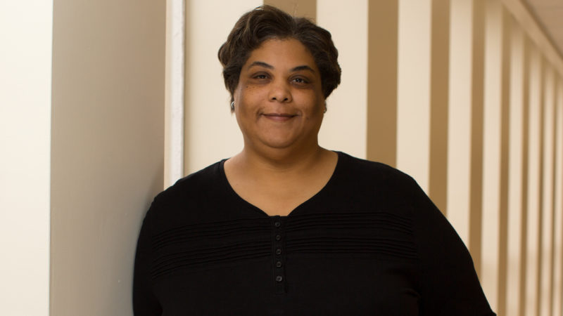 Roxane leaning against a column smiling.