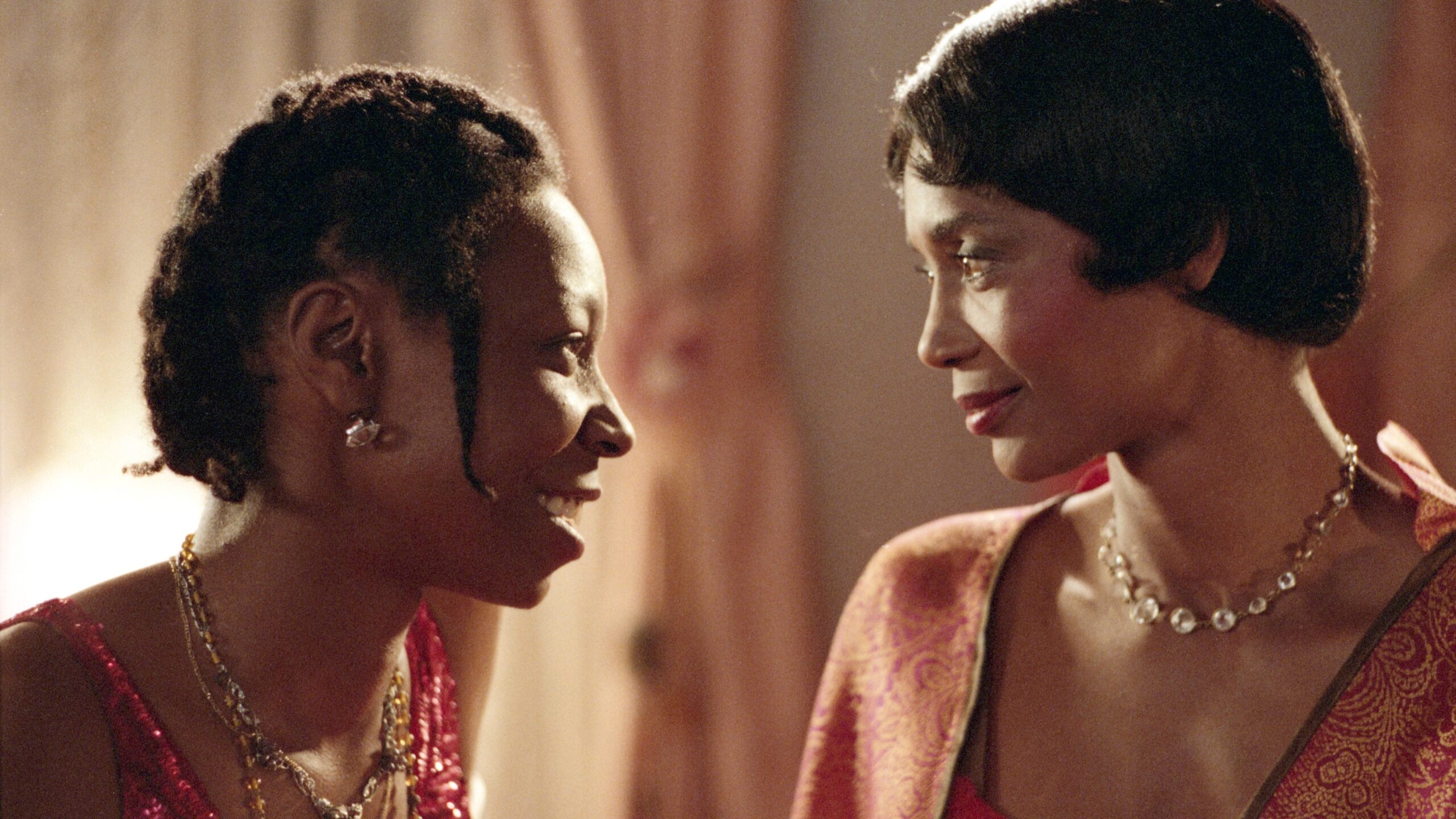 Celie and Shug standing close to eachother. Celie is smiling and both are wearing dresses.