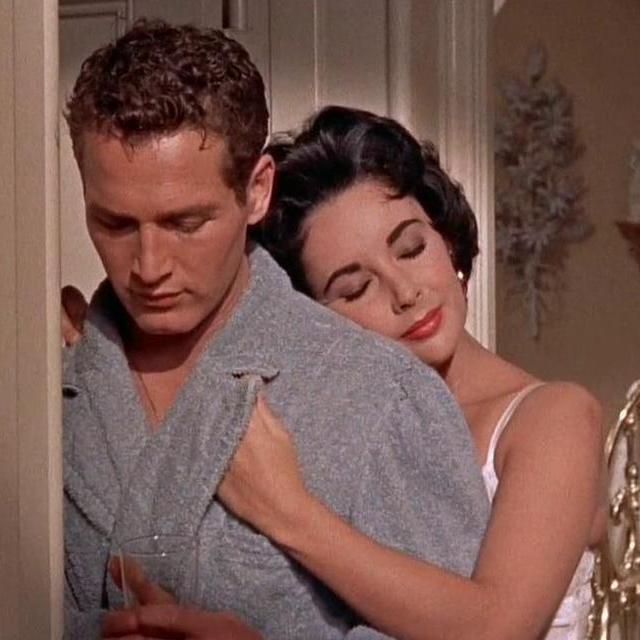 Maggie leaning on Brick's shoulder with her eyes closed, Brick looks down. they are wearing bath robes.