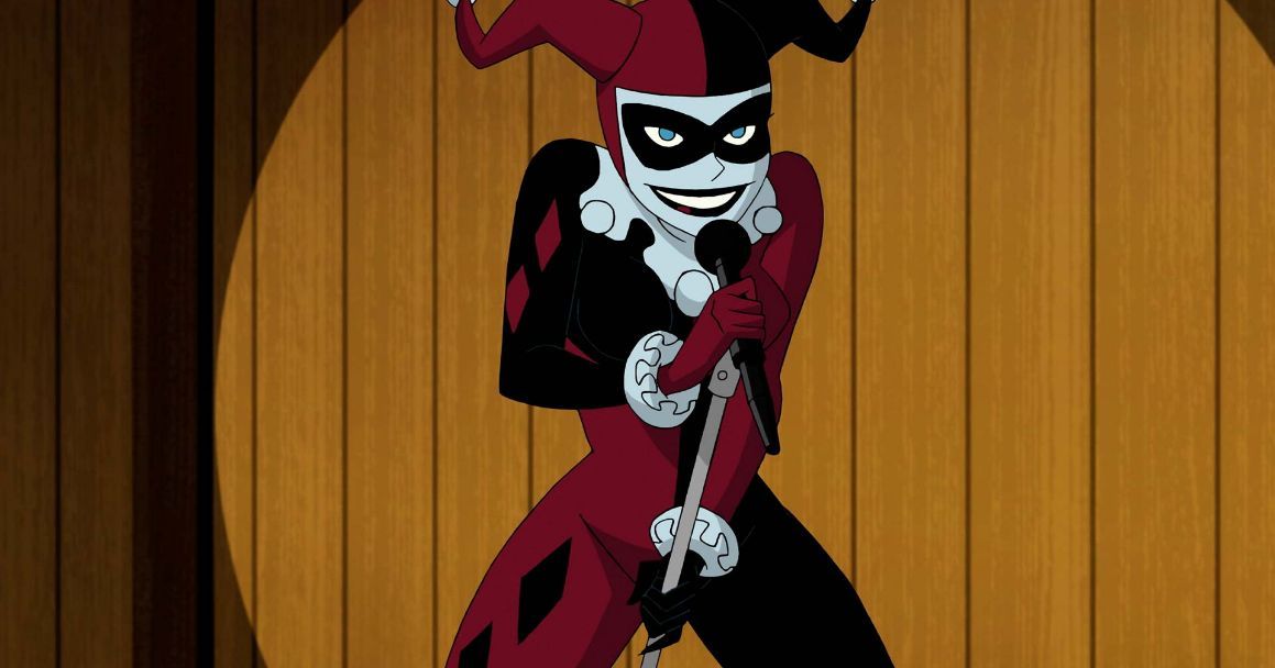 Harley Quinn con su traje de villana, frente a una audiencia con un micr&oacute;fono en la mano.