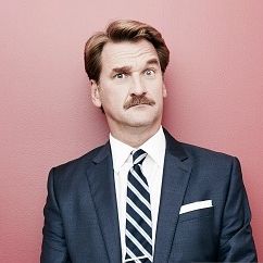 Darryl against a pink background with a confused expression on his face.