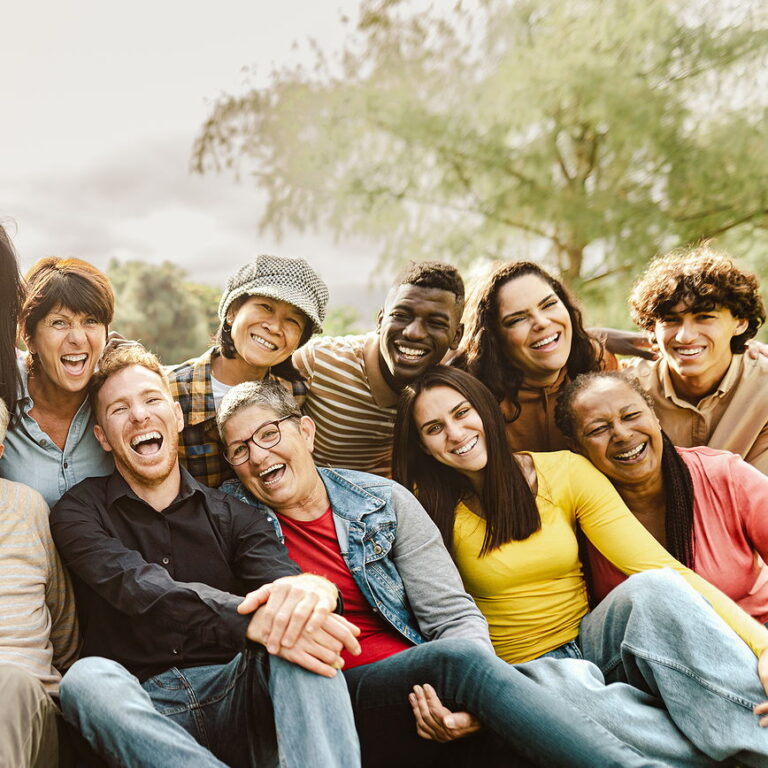 The silhouette of 4 people running through the water at a beach. the sun is reflecting all the water in the air.
