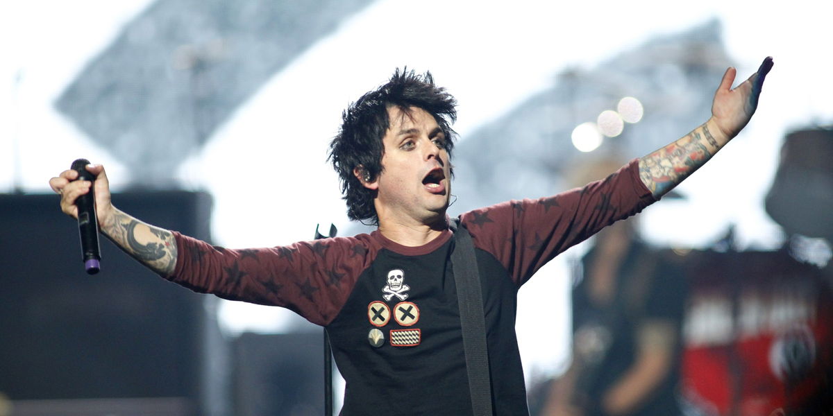 Billie Joe en un concierto, promocionando a la audiencia con las manos extendidas.