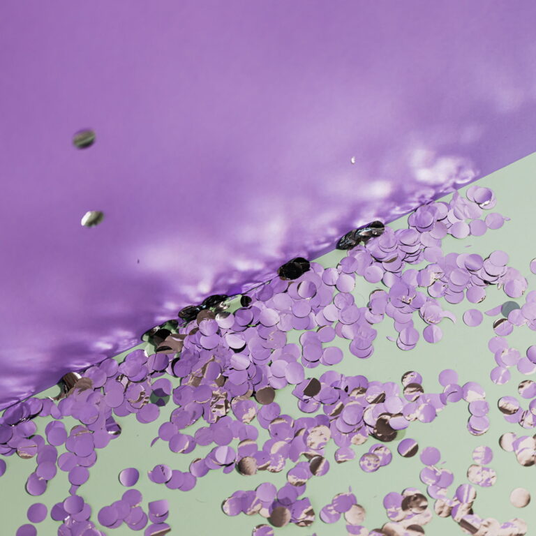 A purple wall cuts across a floor with purple confetti on the ground.