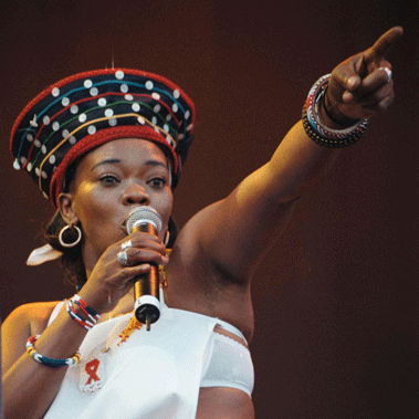 Brenda Fassie at a concert singing into the mic and pointing to the audience.