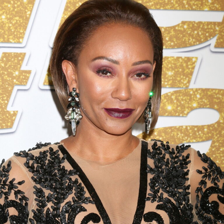 Mel B at a carpet event smiling to the camera.