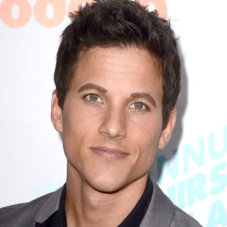 Mike Manning at a carpet event wearing a suit and smiling to the camera.