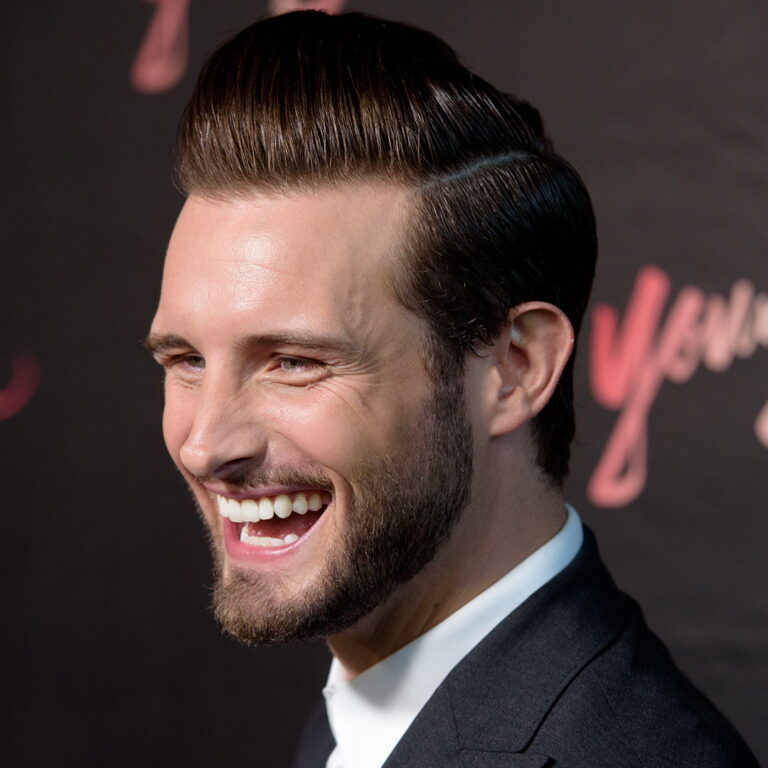 Nico at a carpet event, wearing a suit and smiling to the camera.
