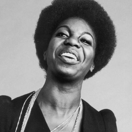 Black and white image of Nina looking to her side laughing.