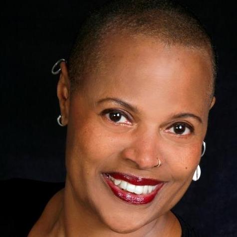 Portrait of Sapphire smiling against a dark background.