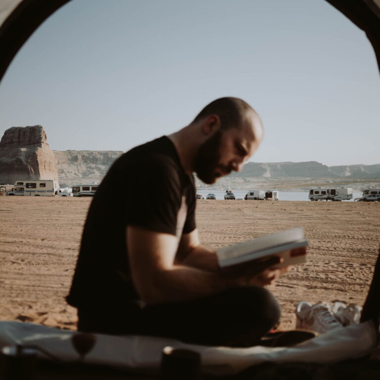 A man dressed in black, sitting reading a book.