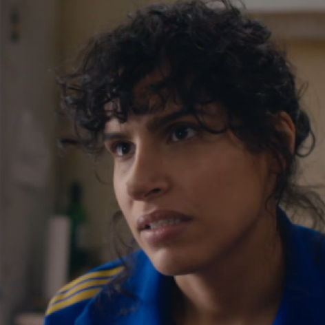 Leila in the series "The Bisexual" wearing a work uniform with a concern expression.