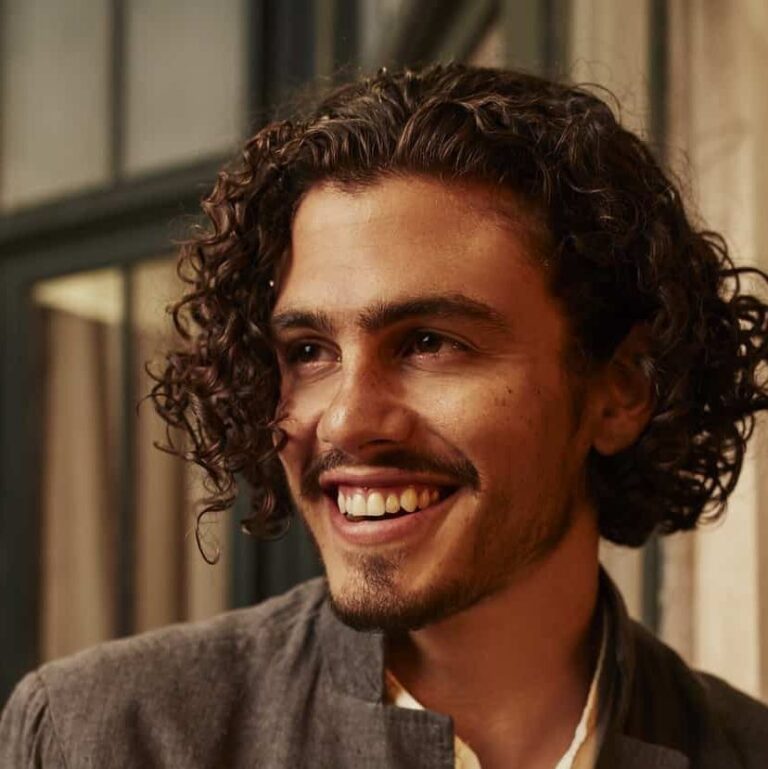 Gael looking to his side smiling while outdoors.