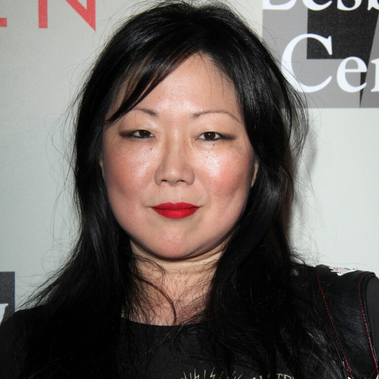 Margaret Cho at a carpet event, her hair down and a smirk on her face.