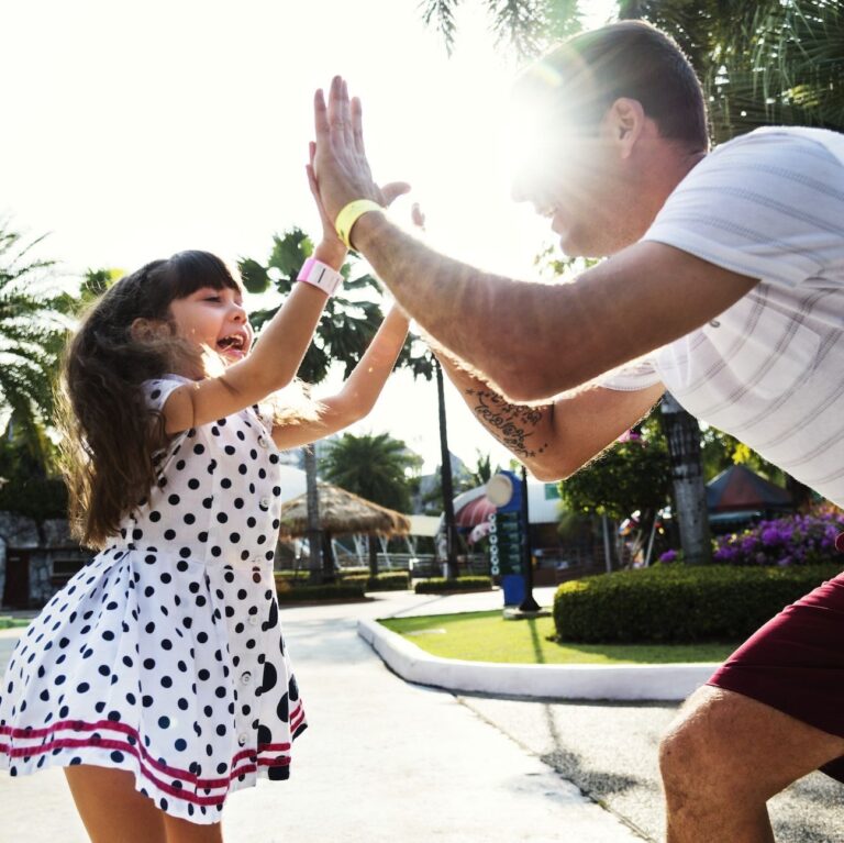 A man high gives a young girl while in the street on a sunny day.