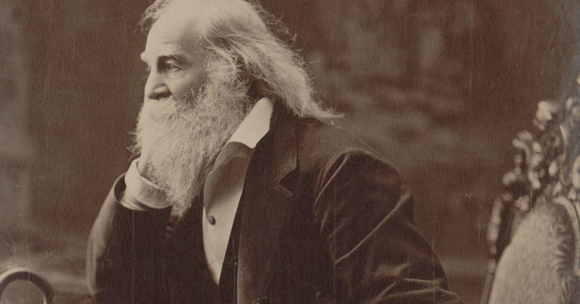 Imagen en tono sepia de un Walt mayor con una gran barba, con la mano en la barbilla contemplando y mirando algo fuera de marco.