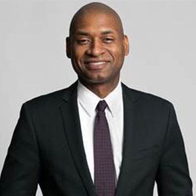 Charles wearing a dark colored suit and smiling to the camera.