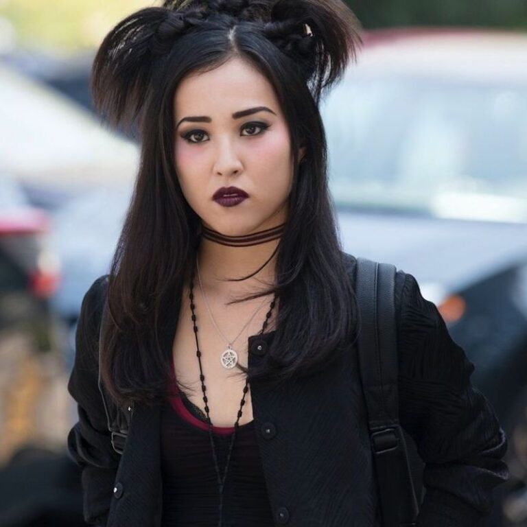 Nico wearing her goth clothing and has a serious look towards the camera.