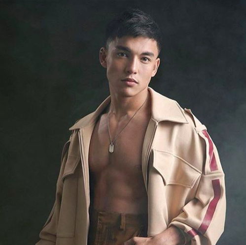 Alex Diaz posing with a coat against a plain background with the front exposing his chest.