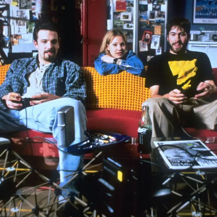 Holden Banken sit on the couch playing a videogame while Alyssa is sitting behind them watching them play