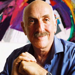 Fritz Klein wearing a blue collared shirt and a smile against a colorful background.