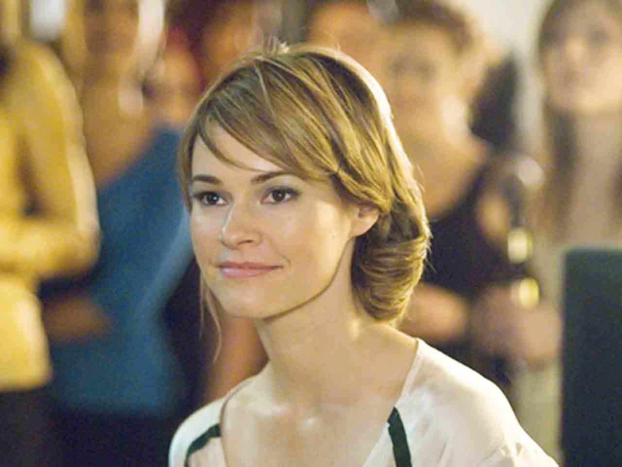 Alice smiling, at an event, looking at someone out of frame.