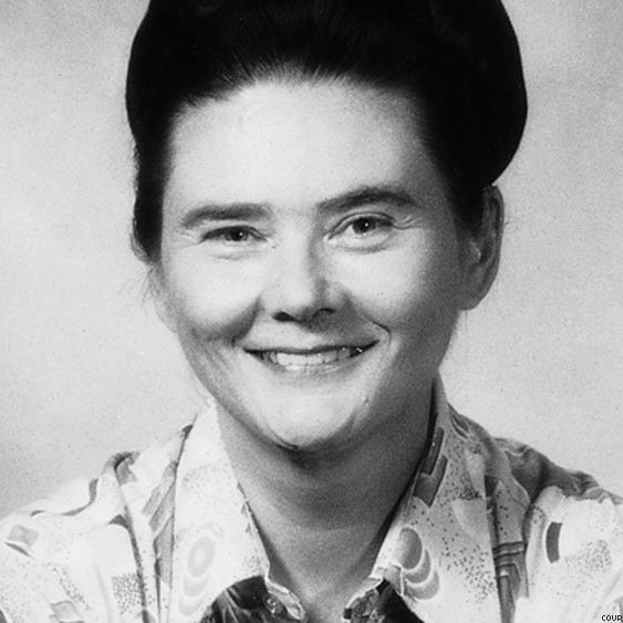 A black and white image of Florence smiling wearing a buttoned up shirt.