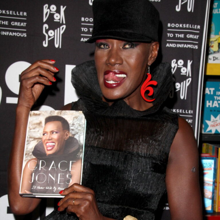 Grace Jones with her book and her tongue out smiling.