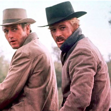 Butch and Sundance sharing a horse both turned with concerned expressions looking behind them.