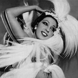 Josephine Baker in the middle of a dance wearing a dress of that time, in white, smiling looking away from the camera.