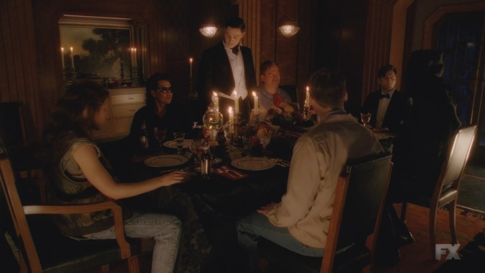 Escena de Devil's Night donde varios asesinos en serie se sientan juntos alrededor de una mesa compartiendo una comida mientras March brinda un brindis.