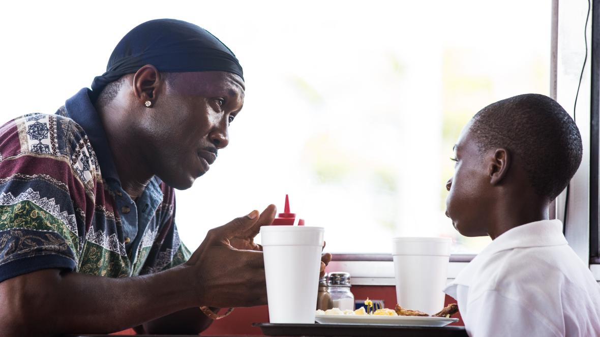Juan and a young Chiron sit together at a diner while Juan explains something to Chiron.