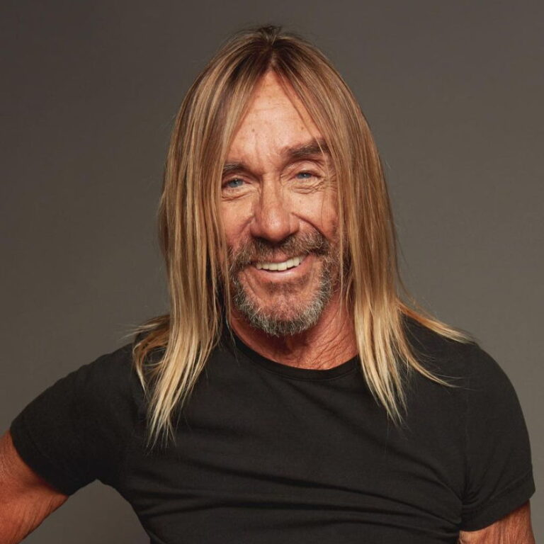 Iggy Pop smiling against a plain background.