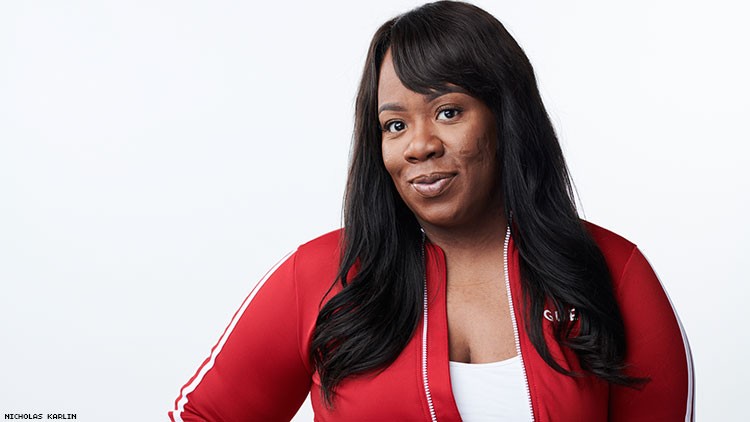 Franqi French smirking to the camera wearing a tracksuit and shirt.